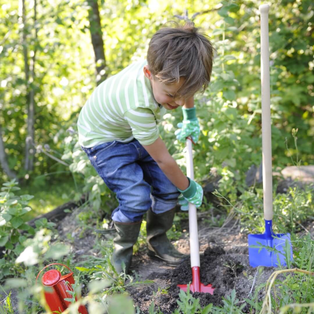 Young child digging in the garden with Gluckskafer metal spade and children's gardening tools from Mercurius in Australia